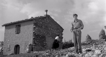 Movie still from “Two Women” (1960), directed by Vittorio De Sica – A man and a woman standing in front of an old stone building; Wide shot, Low angle