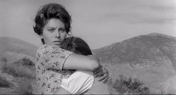 Movie still from “Two Women” (1960), directed by Vittorio De Sica – A woman hugging another woman while standing on top of a hill; Medium shot, Low angle
