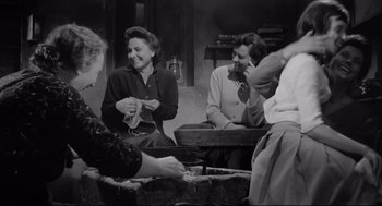 Movie still from “Two Women” (1960), directed by Vittorio De Sica – A group of people sitting around a table; Medium shot, Low angle