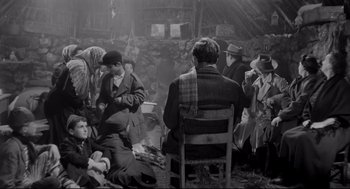 Movie still from “Two Women” (1960), directed by Vittorio De Sica – A black and white photo of a group of people sitting around a fire; Wide shot, High angle