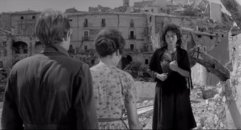 Movie still from “Two Women” (1960), directed by Vittorio De Sica – A group of people standing on top of a dirt field; Wide shot, Over the shoulder angle