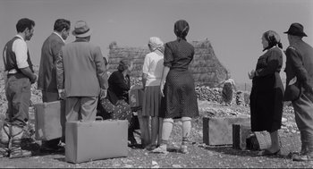 Movie still from “Two Women” (1960), directed by Vittorio De Sica – A black and white photo of a group of people standing next to a pile of suitcases; Wide shot, Low angle