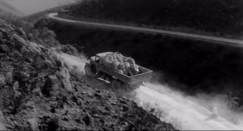 An old truck hauling a load of sheep down a dirt road