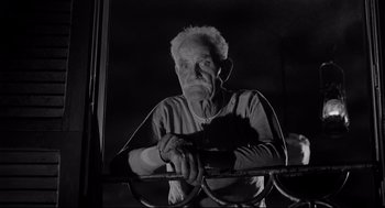 Movie still from “Two Women” (1960), directed by Vittorio De Sica – An old man holding a cat while standing next to a window; Medium shot, Low angle