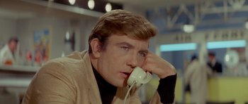 Movie still from “Two for the Road” (1967), directed by Stanley Donen – A young man holding a phone up to his face; Close Up shot, High angle