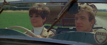 Movie still from “Two for the Road” (1967), directed by Stanley Donen – A woman sitting in a car with a man in the back seat; Close Up shot, Low angle