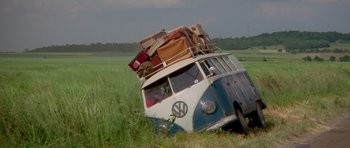 Movie still from “Two for the Road” (1967), directed by Stanley Donen – An old vw bus with luggage on top of it in a grassy field; Wide shot, Low angle