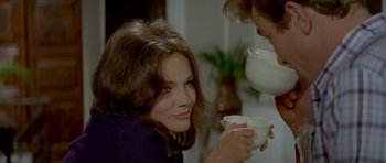 Movie still from “Two for the Road” (1967), directed by Stanley Donen – A woman sitting at a table holding a white cup; Close Up shot, Over the shoulder angle