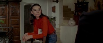 Movie still from “Two for the Road” (1967), directed by Stanley Donen – A woman in a red shirt is leaning on a chair; Medium shot, Low angle