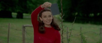Movie still from “Two for the Road” (1967), directed by Stanley Donen – A woman in a red sweater holding a book in her hand; Close Up shot, High angle