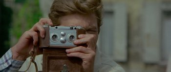Movie still from “Two for the Road” (1967), directed by Stanley Donen – A man taking a picture with an old fashioned camera; Extreme Close Up shot, Over the shoulder angle
