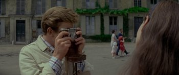 Movie still from “Two for the Road” (1967), directed by Stanley Donen – A man taking a picture of a crowd of onlookers; Close Up shot, Over the shoulder angle