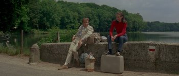 Movie still from “Two for the Road” (1967), directed by Stanley Donen – A man and a woman sitting on a wall next to suitcases; Medium shot, High angle