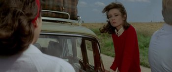 Movie still from “Two for the Road” (1967), directed by Stanley Donen – A woman in a red sweater standing next to a car; Medium shot, Over the shoulder angle