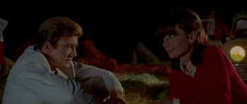 Movie still from “Two for the Road” (1967), directed by Stanley Donen – A man and a woman sitting in a field at night; Medium shot, Over the shoulder angle