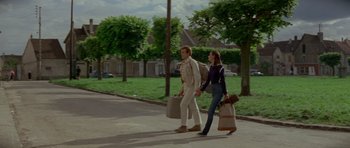 Movie still from “Two for the Road” (1967), directed by Stanley Donen – A man and a woman walking down a street holding bags; Wide shot, Low angle