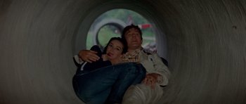 Movie still from “Two for the Road” (1967), directed by Stanley Donen – A man and a woman laying on the ground in a tunnel; Medium shot, High angle