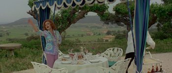 Movie still from “Two for the Road” (1967), directed by Stanley Donen – A woman standing next to a table set for a meal; Wide shot, Over the shoulder angle