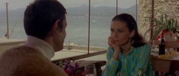 Movie still from “Two for the Road” (1967), directed by Stanley Donen – A man and a woman sitting in front of each other at a table; Medium shot, Over the shoulder angle