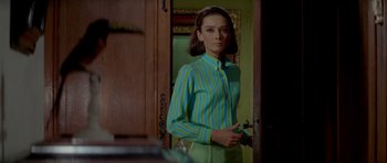 Movie still from “Two for the Road” (1967), directed by Stanley Donen – A woman standing in front of a mirror in a room; Medium shot, Over the shoulder angle