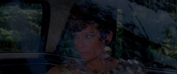 Movie still from “Two for the Road” (1967), directed by Stanley Donen – A woman with long earrings is seen through a glass window; Close Up shot, Over the shoulder angle