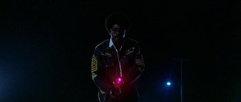 Movie still from “Two-Lane Blacktop” (1971), directed by Monte Hellman – A man standing in the dark holding a red light; Medium shot, Low angle