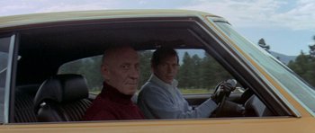 Movie still from “Two-Lane Blacktop” (1971), directed by Monte Hellman – Two men sitting in the drivers seat of a yellow car; Medium shot, Low angle