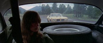 Movie still from “Two-Lane Blacktop” (1971), directed by Monte Hellman – A woman sitting in the driver's seat of a car looking out the window; Wide shot, High angle