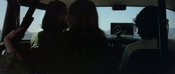 Movie still from “Two-Lane Blacktop” (1971), directed by Monte Hellman – Two people in a car looking out the window; Medium shot, Over the shoulder angle