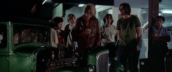 Movie still from “Two-Lane Blacktop” (1971), directed by Monte Hellman – A group of people standing next to an old green truck; Medium shot, Low angle