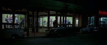 Movie still from “Two-Lane Blacktop” (1971), directed by Monte Hellman – A car parked in front of a building at night; Extreme Wide shot, Low angle