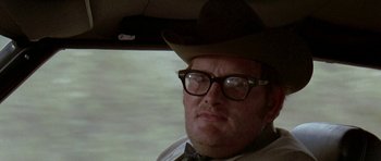 Movie still from “Two-Lane Blacktop” (1971), directed by Monte Hellman – A man wearing glasses and a cowboy hat in a car; Close Up shot, Low angle