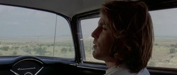 Movie still from “Two-Lane Blacktop” (1971), directed by Monte Hellman – A man sitting in the driver's seat of a car looking out the window; Close Up shot, Low angle