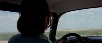 Movie still from “Two-Lane Blacktop” (1971), directed by Monte Hellman – A person sitting in the driver's seat of a car; Medium shot, Over the shoulder angle