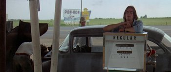 Movie still from “Two-Lane Blacktop” (1971), directed by Monte Hellman – An older man sitting in the driver's seat of an old car; Medium shot, Over the shoulder angle