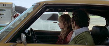 Movie still from “Two-Lane Blacktop” (1971), directed by Monte Hellman – A man and a woman sitting in the drivers seat of a car; Medium shot, Over the shoulder angle