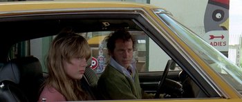Movie still from “Two-Lane Blacktop” (1971), directed by Monte Hellman – A man and a woman sitting in the drivers seat of a car; Medium shot, Low angle