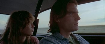 Movie still from “Two-Lane Blacktop” (1971), directed by Monte Hellman – A man and a woman sitting in a car with an open umbrella; Close Up shot, Low angle