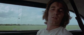 Movie still from “Two-Lane Blacktop” (1971), directed by Monte Hellman – A person with long hair in a car; Close Up shot, Low angle
