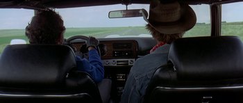 Movie still from “Two-Lane Blacktop” (1971), directed by Monte Hellman – A man driving a car in the middle of the road; Wide shot, High angle