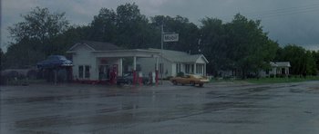 Movie still from “Two-Lane Blacktop” (1971), directed by Monte Hellman – A gas station with a car parked in front of it; Extreme Wide shot, High angle