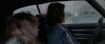 Movie still from “Two-Lane Blacktop” (1971), directed by Monte Hellman – A man and a woman sitting in the back seat of a car; Medium shot, Over the shoulder angle