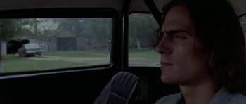 Movie still from “Two-Lane Blacktop” (1971), directed by Monte Hellman – A man sitting in the driver's seat of a car; Close Up shot, Low angle