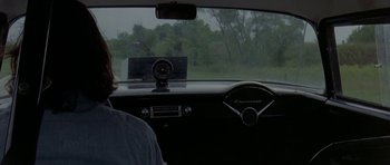 Movie still from “Two-Lane Blacktop” (1971), directed by Monte Hellman – A man is driving a car in the rain; Medium shot, Over the shoulder angle
