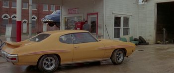Movie still from “Two-Lane Blacktop” (1971), directed by Monte Hellman – An old car parked in front of a gas station; Wide shot, Low angle