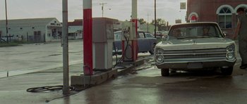 Movie still from “Two-Lane Blacktop” (1971), directed by Monte Hellman – An old gas station with cars parked at the gas pumps; Wide shot, High angle