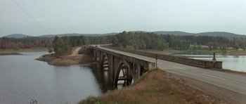 Movie still from “Two-Lane Blacktop” (1971), directed by Monte Hellman – A bridge over a body of water near a wooded area; Extreme Wide shot, High angle
