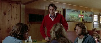 Movie still from “Two-Lane Blacktop” (1971), directed by Monte Hellman – A man in a red sweater standing in front of a woman; Medium shot, Over the shoulder angle