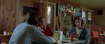 Movie still from “Two-Lane Blacktop” (1971), directed by Monte Hellman – A group of people sitting around a table; Medium shot, Over the shoulder angle