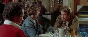 Movie still from “Two-Lane Blacktop” (1971), directed by Monte Hellman – Two men sitting at a table in front of each other at a restaurant; Medium shot, Over the shoulder angle